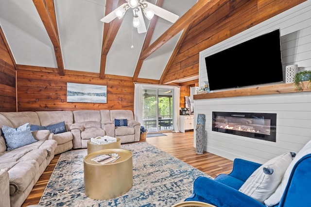 living room featuring light hardwood / wood-style flooring, beam ceiling, a fireplace, high vaulted ceiling, and wood walls