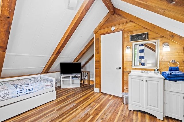 bedroom with wood walls, vaulted ceiling with beams, and light hardwood / wood-style floors