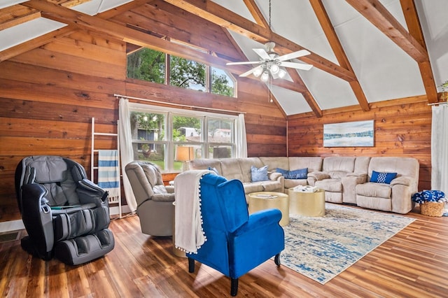 living room with beamed ceiling, wooden walls, ceiling fan, hardwood / wood-style flooring, and high vaulted ceiling