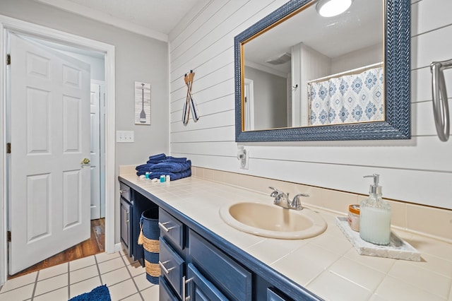 bathroom with crown molding, tile patterned floors, vanity, and wood walls