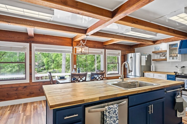 kitchen with sink, butcher block countertops, blue cabinets, an island with sink, and stainless steel appliances