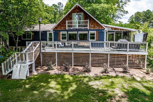 rear view of house with a lawn, a sunroom, and a wooden deck