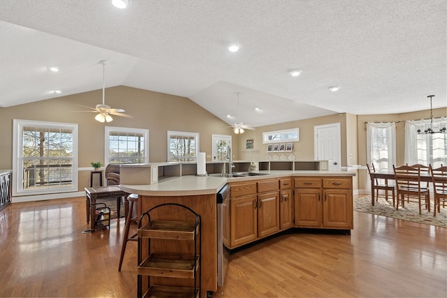 kitchen featuring light countertops, light wood finished floors, ceiling fan with notable chandelier, and a sink