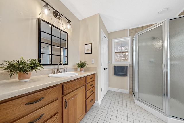 full bathroom with a stall shower, vanity, baseboards, and tile patterned floors