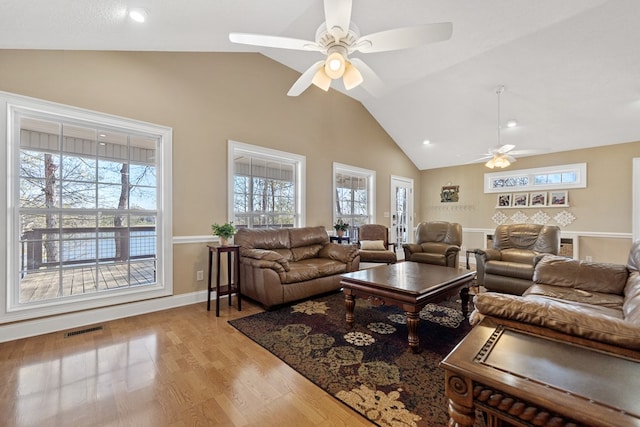 living area featuring visible vents, light wood-style flooring, a ceiling fan, and plenty of natural light