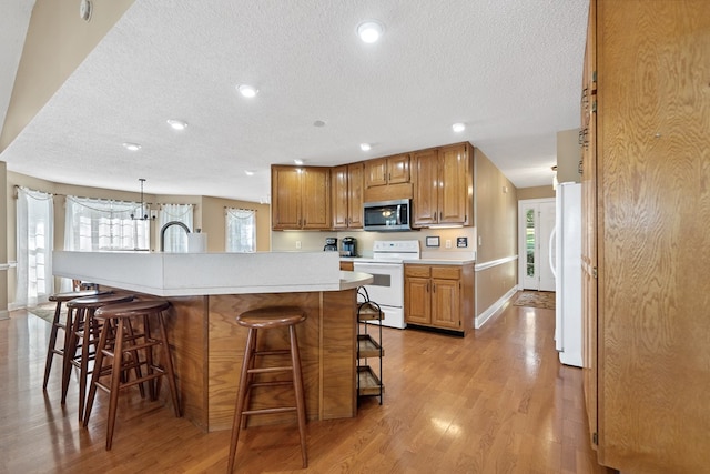 kitchen featuring a textured ceiling, white appliances, and a kitchen breakfast bar