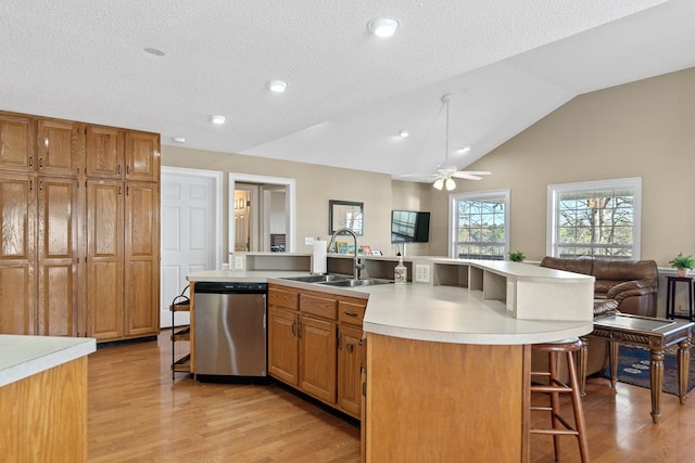 kitchen with stainless steel dishwasher, light wood-type flooring, a kitchen bar, and a sink