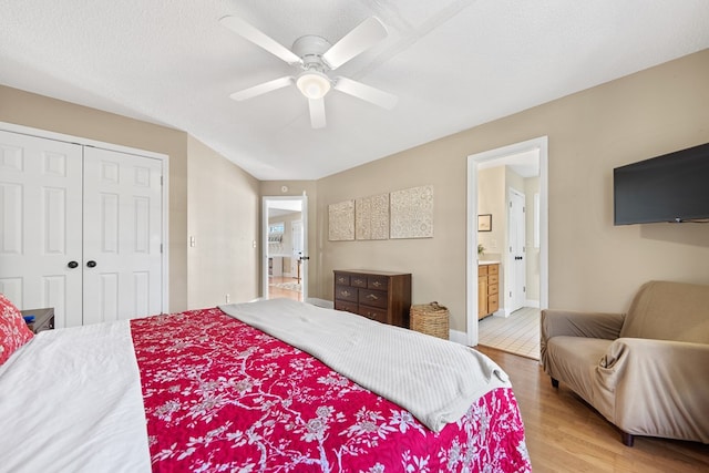 bedroom with a closet, a ceiling fan, ensuite bath, vaulted ceiling, and wood finished floors