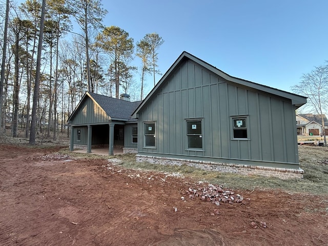 rustic home featuring roof with shingles, board and batten siding, and a patio area