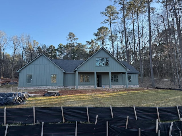 view of front of property with roof with shingles, board and batten siding, and a front yard