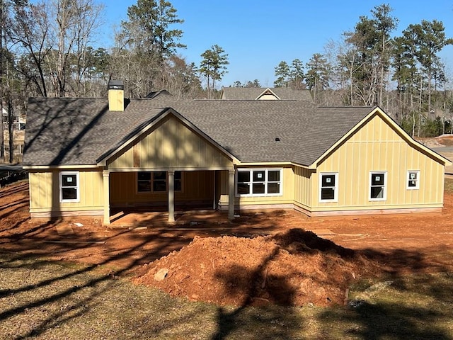 rear view of property with a shingled roof and a chimney