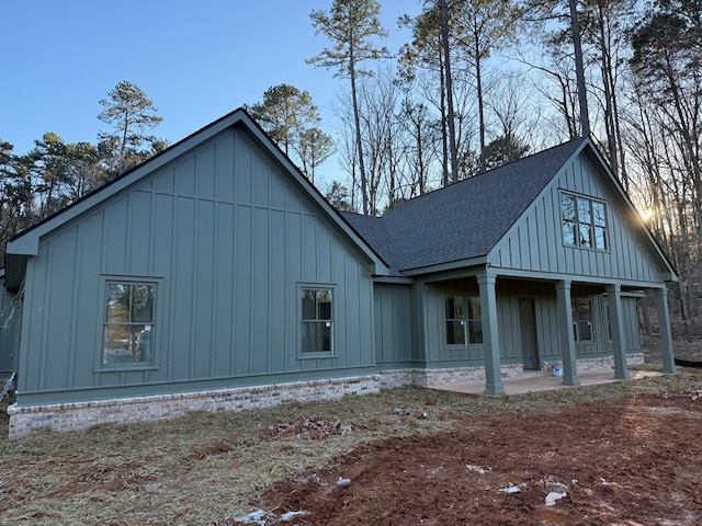 view of front facade featuring a patio, board and batten siding, and roof with shingles