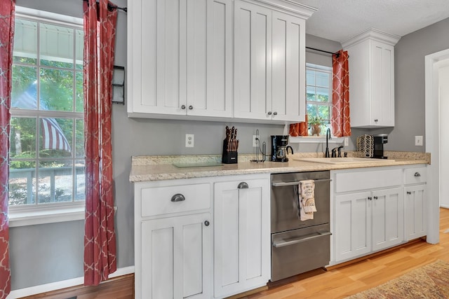 kitchen featuring dishwasher, sink, light hardwood / wood-style flooring, a textured ceiling, and white cabinetry