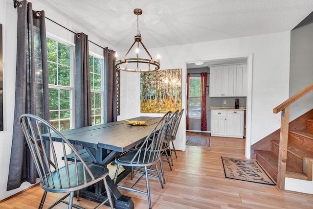 dining room featuring light hardwood / wood-style floors, a textured ceiling, and an inviting chandelier