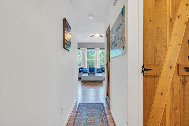 hallway with hardwood / wood-style flooring and a textured ceiling