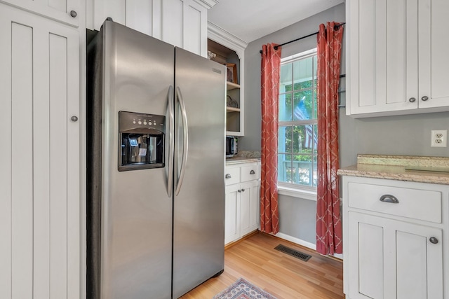 kitchen featuring light hardwood / wood-style floors, stainless steel fridge, white cabinetry, and a wealth of natural light