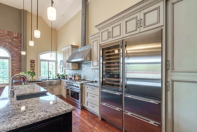 kitchen with decorative backsplash, cream cabinetry, decorative light fixtures, and high end appliances