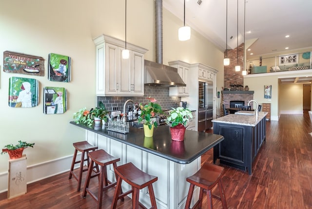 kitchen with a kitchen breakfast bar, a towering ceiling, backsplash, pendant lighting, and a center island with sink