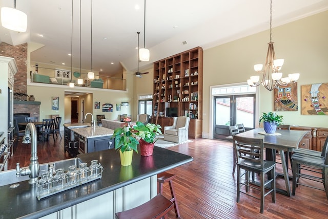 kitchen featuring a kitchen bar, a center island with sink, a fireplace, a high ceiling, and hanging light fixtures