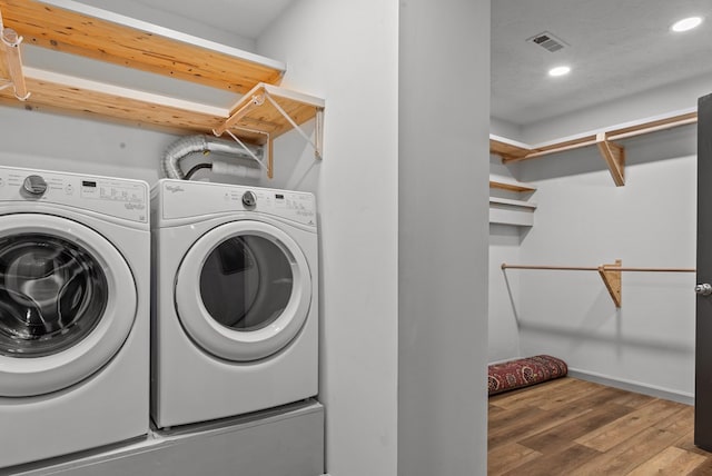 washroom with hardwood / wood-style flooring, a textured ceiling, and washing machine and clothes dryer