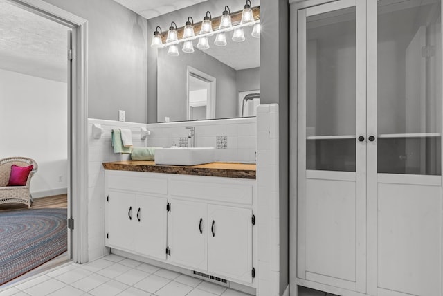 bathroom with tile patterned flooring, vanity, and a textured ceiling