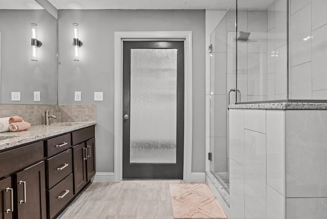 bathroom featuring decorative backsplash, vanity, and an enclosed shower