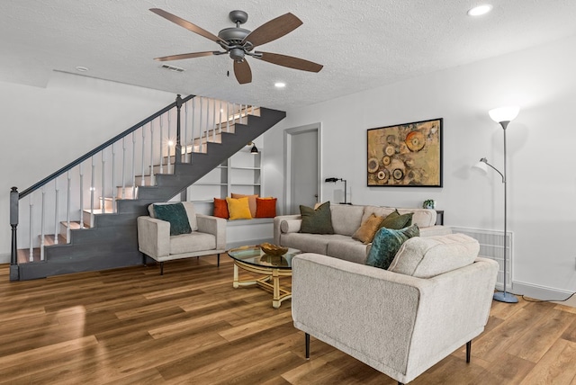 living room with hardwood / wood-style floors, a textured ceiling, and ceiling fan