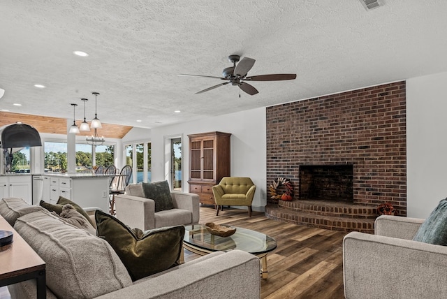 living room with ceiling fan, a fireplace, dark hardwood / wood-style floors, and a textured ceiling