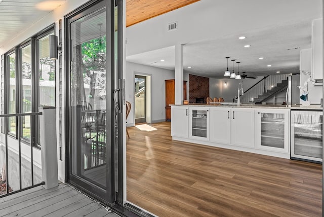 interior space with wine cooler, white cabinets, pendant lighting, and hardwood / wood-style flooring