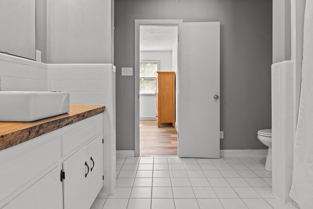 bathroom with tile patterned floors, vanity, toilet, and a textured ceiling