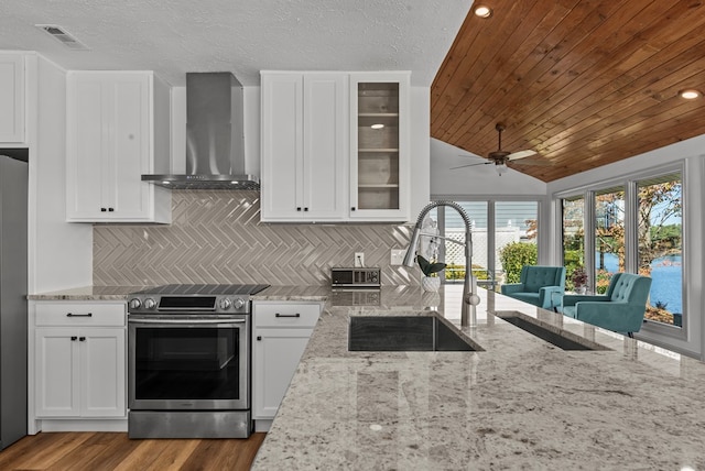 kitchen with decorative backsplash, appliances with stainless steel finishes, light stone counters, wall chimney exhaust hood, and wood ceiling