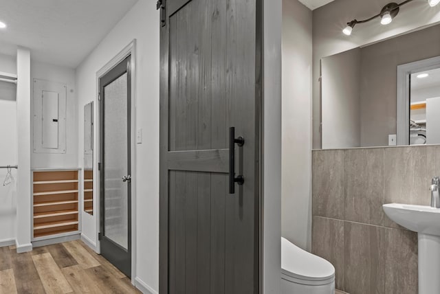 bathroom featuring hardwood / wood-style floors, electric panel, and toilet