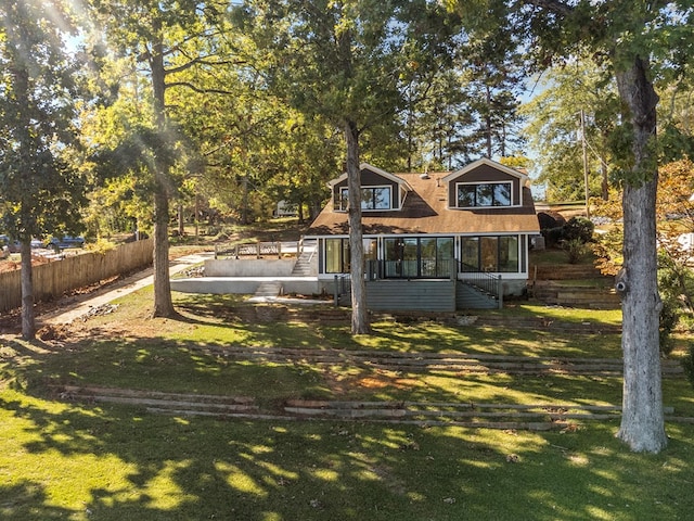 rear view of house featuring a lawn and a sunroom