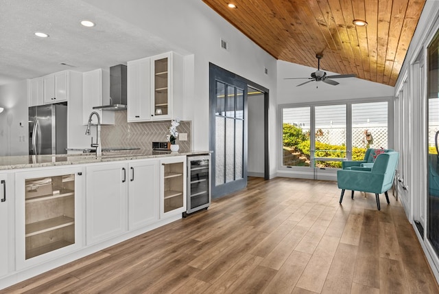 kitchen featuring white cabinetry, wall chimney exhaust hood, wine cooler, vaulted ceiling, and wood ceiling