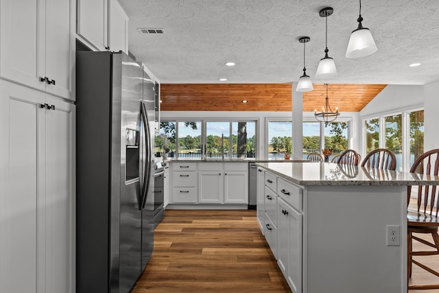 kitchen with white cabinetry, a center island, a kitchen breakfast bar, pendant lighting, and appliances with stainless steel finishes