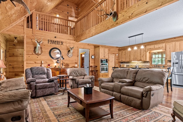 living room with wood walls, sink, a towering ceiling, and hardwood / wood-style floors