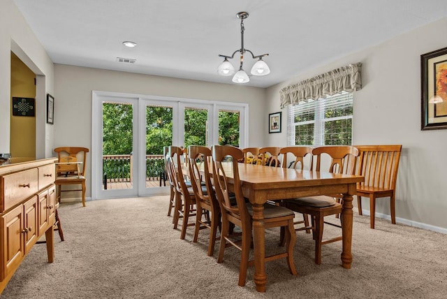 carpeted dining space with an inviting chandelier