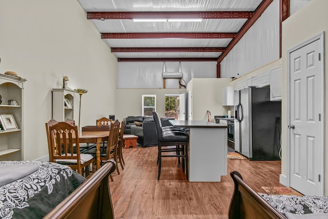 kitchen featuring a kitchen breakfast bar, light hardwood / wood-style flooring, beamed ceiling, kitchen peninsula, and stainless steel appliances