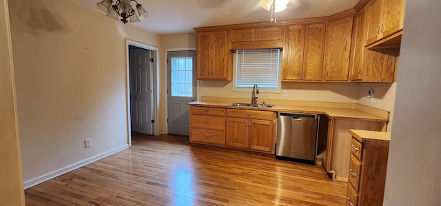 kitchen featuring brown cabinets, light countertops, stainless steel dishwasher, light wood-style floors, and a sink