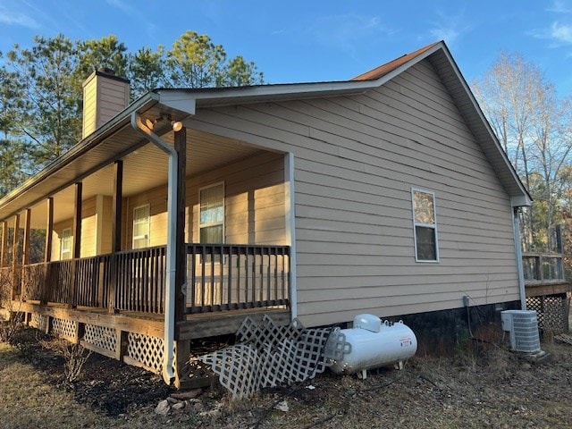 view of side of property featuring a chimney, central AC unit, and a porch