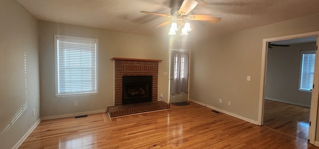 unfurnished living room featuring visible vents, baseboards, a ceiling fan, light wood-style floors, and a fireplace