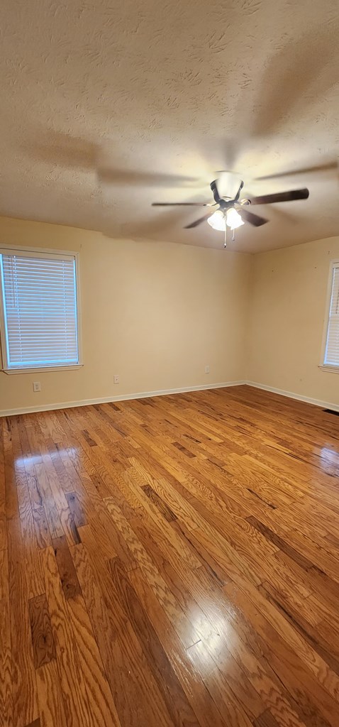 empty room featuring ceiling fan, a textured ceiling, visible vents, baseboards, and light wood-style floors