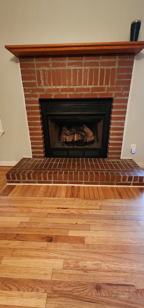 interior details with a brick fireplace, baseboards, and wood finished floors