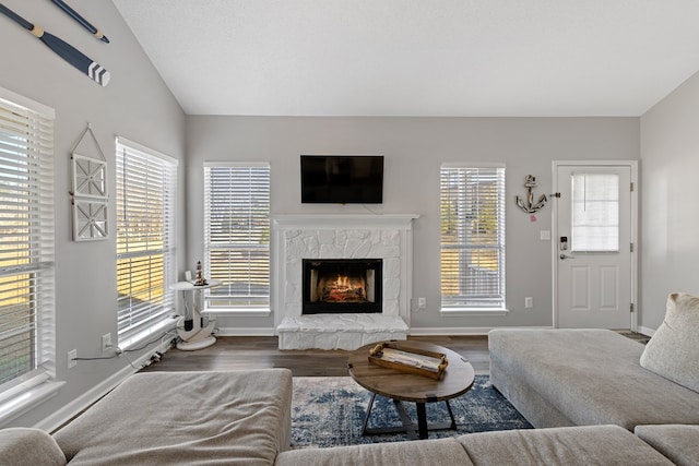 living room featuring lofted ceiling, dark wood-style floors, a fireplace, and baseboards