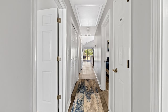 hall with attic access and wood finished floors