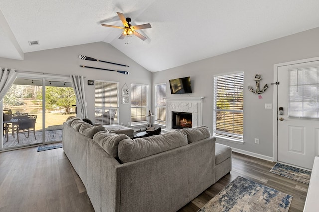 living room with vaulted ceiling, a wealth of natural light, a ceiling fan, and a high end fireplace