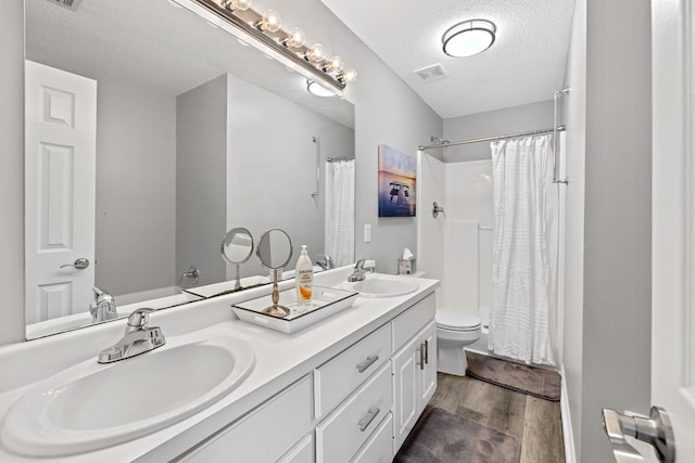 full bath with wood finished floors, a textured ceiling, toilet, and a sink