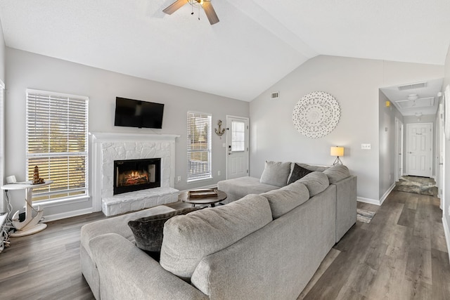 living room featuring dark wood finished floors, vaulted ceiling, a fireplace, and visible vents