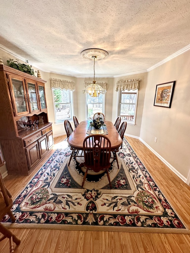 dining space featuring a chandelier, a textured ceiling, baseboards, light wood-style floors, and crown molding