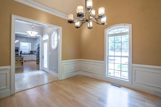 116 Island Dr, Milledgeville, GA 31061 - unfurnished dining area with light wood-style floors, a chandelier, wainscoting, crown molding, and a decorative wall